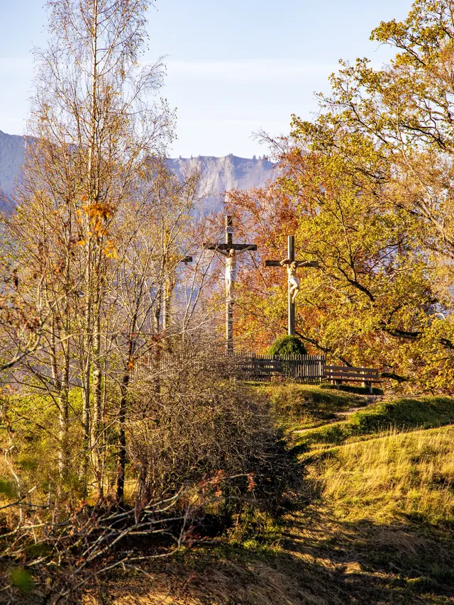 Two wooden crosses among autumn-colored trees on a hilltop
