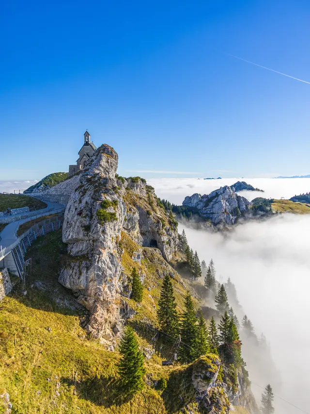 Rocky ridge with a tower above a sea of clouds under a blue sky